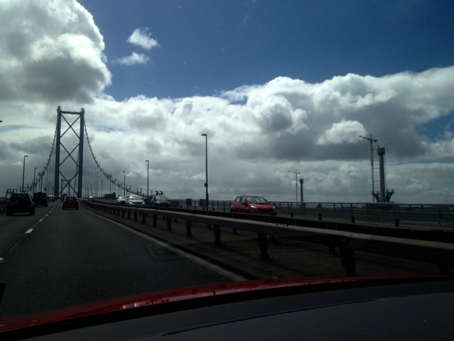 Crossing the Forth Road Bridge beneath a dramatically cloudy sky, you can just see one tower of the new bridge over to the right. 